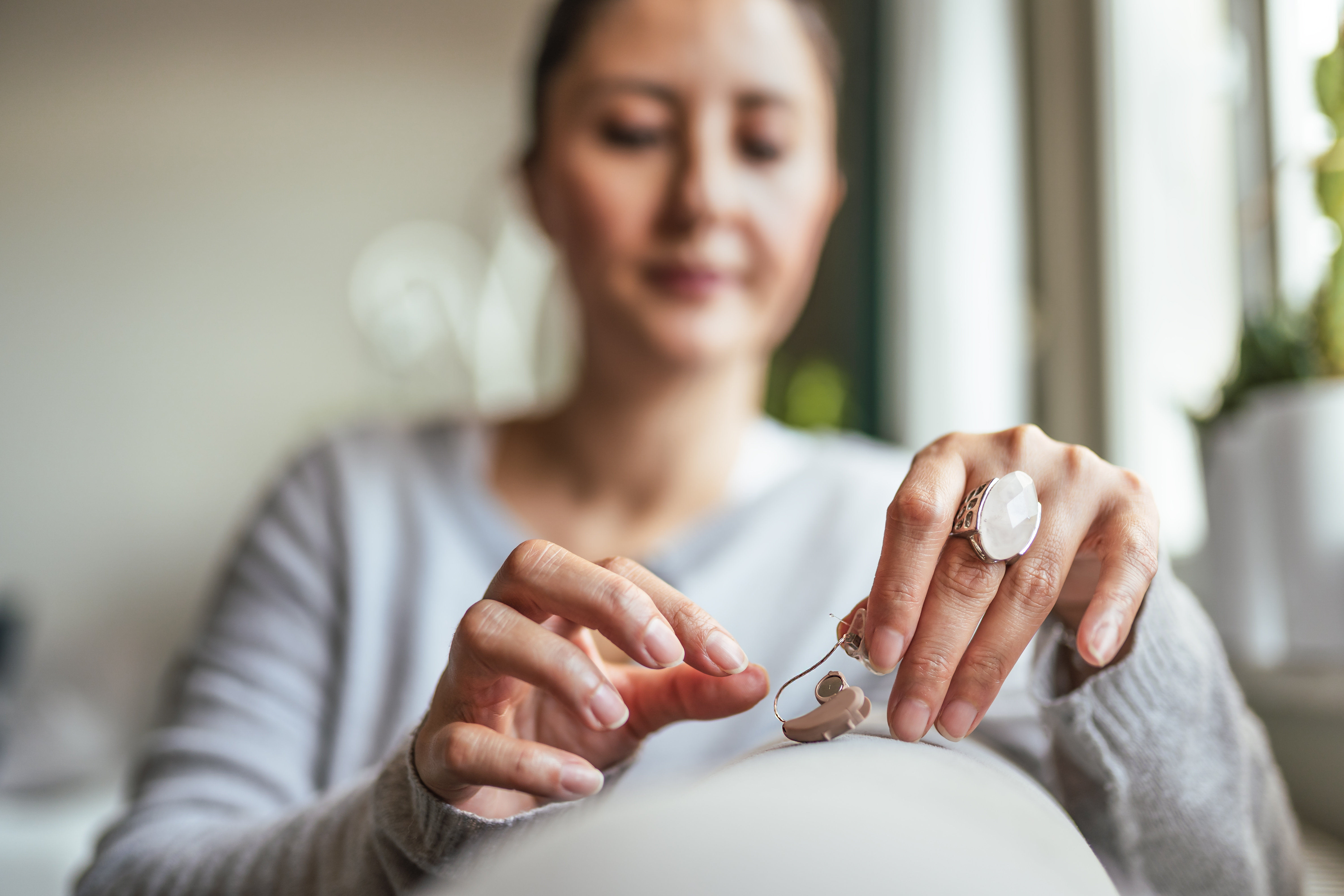 Young adult woman inserting battery into a hearing aid