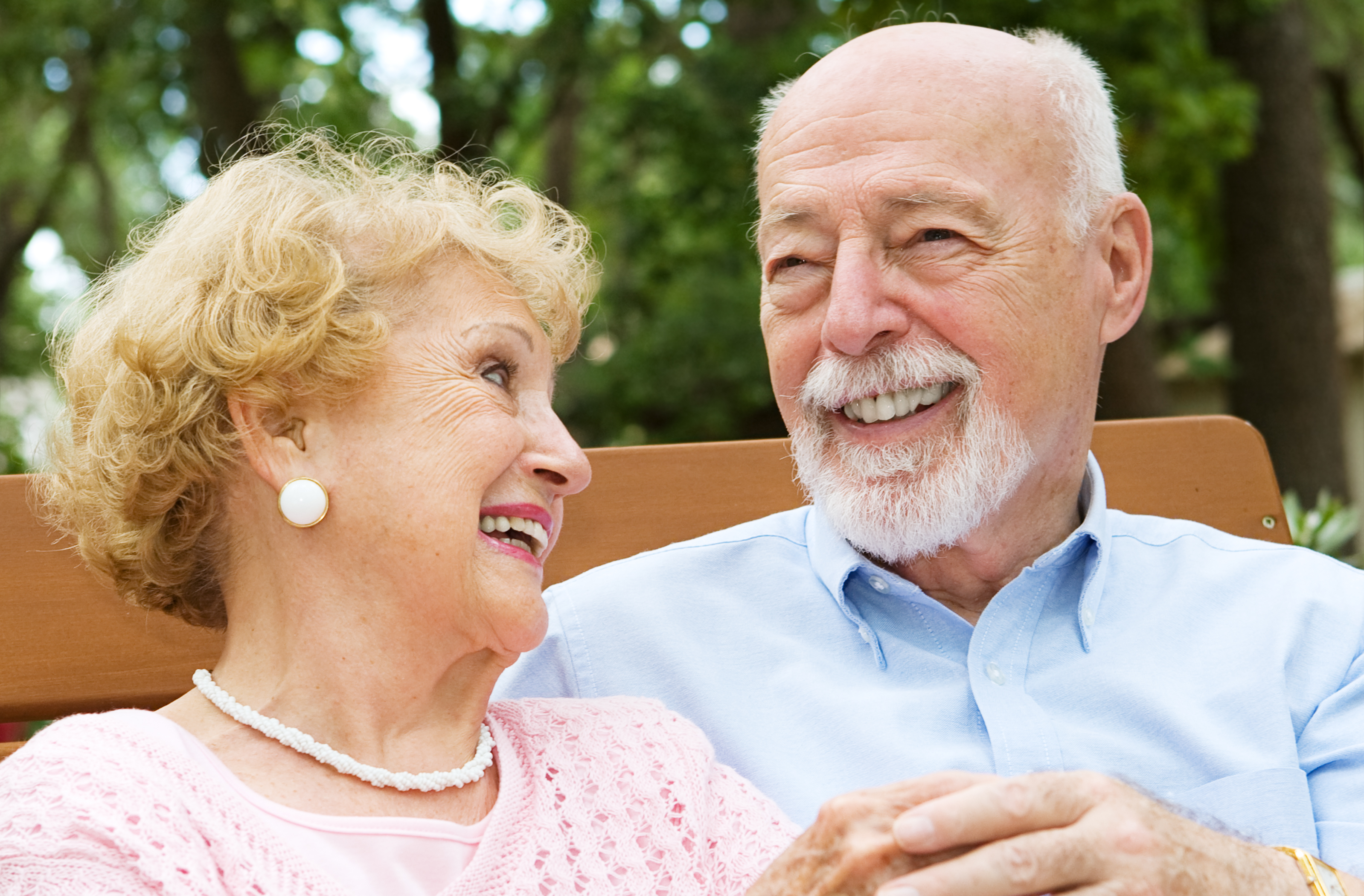 Happy senior couple laughing together.  She is wearing a hearing aid.