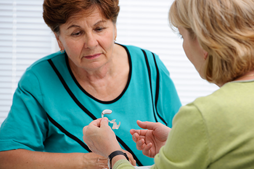 Woman discussing hearing aid with technician.