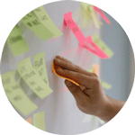 A hand putting up a post-it note on a planning board