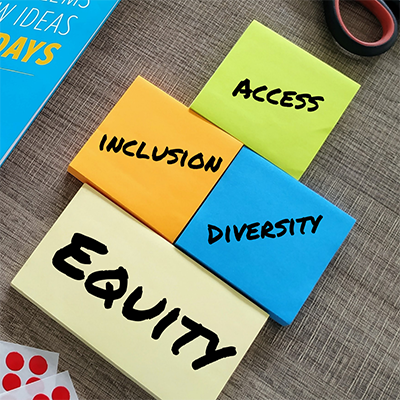 Four sticky pads on a desk with each having one of the words, access, inclusion, diversity, or equity, written on it
