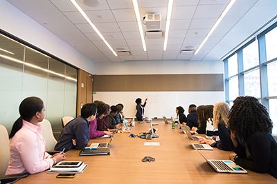 Photo of large meeting taking place around a table in a long room by Christina @ wocintechchat.com 