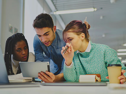 A group of three people looking at a laptop