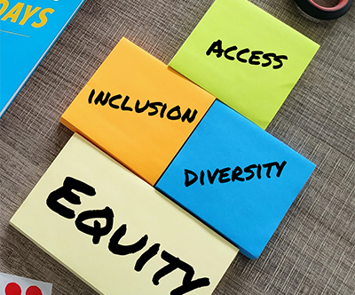 Four sticky pads on a desk with each having one of the words, access, inclusion, diversity, or equity, written on it