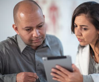 Doctor in clinic explaining results to family using auto generated captions on a tablet 