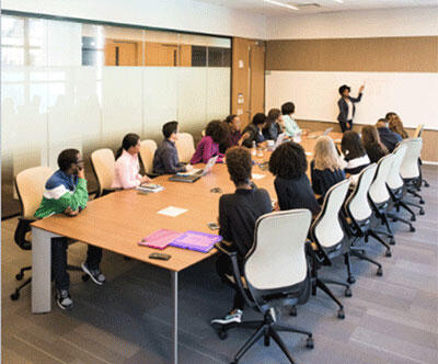 Photo of large meeting taking place around a table in a long room