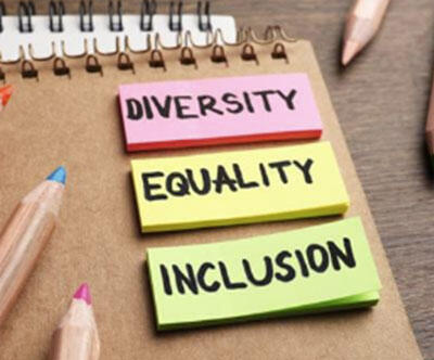 Three sticky pads on a desk with each having one of the words, diversity, inclusion, or inclusion written on it