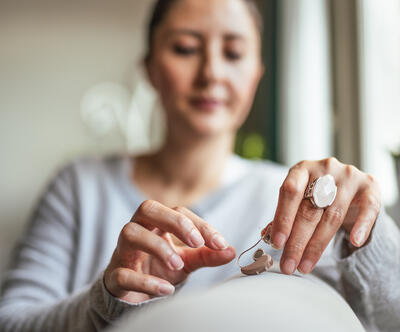 A woman looking at the hearing device she is holding