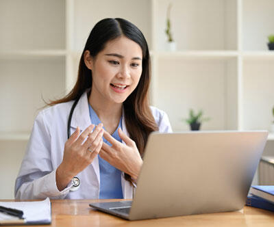 A young doctor talking to a patient on her laptop