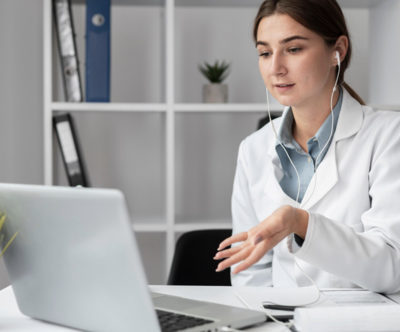 An audiologist sits in front of her computer providing teleaudiology services.