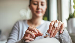 Young adult woman inserting battery into a hearing aid