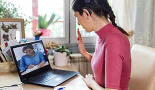 Young woman with cochlear implant studying online at home. She using modern technology.