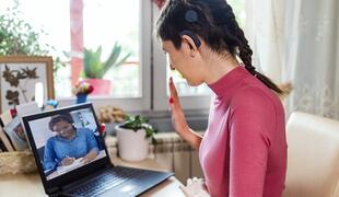 Young woman with cochlear implant studying online at home. She using modern technology.